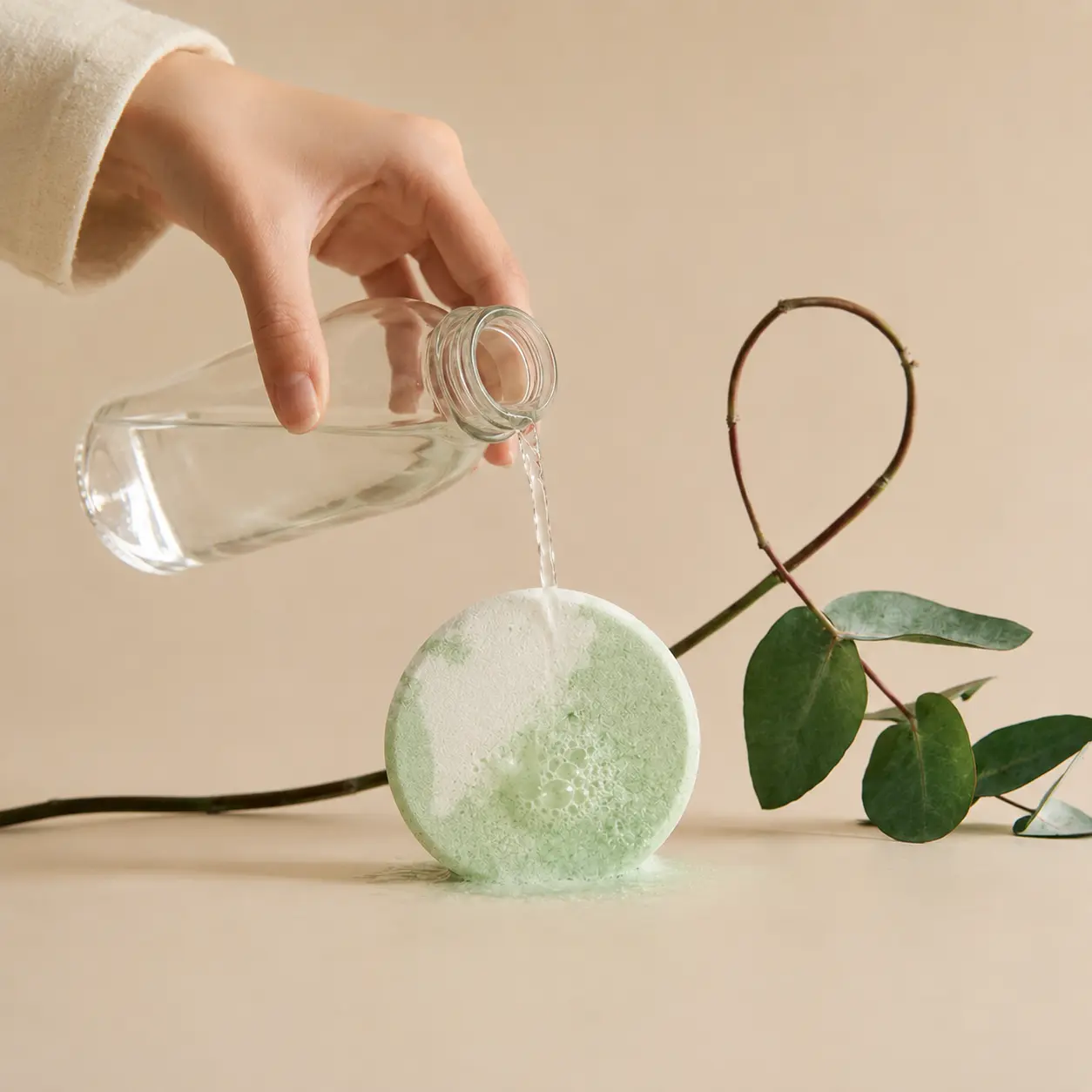 Holy Fizz Eucalyptus Boost Shower Steamer fizzing with water poured from glass bottle eucalyptus branch home spa how to use