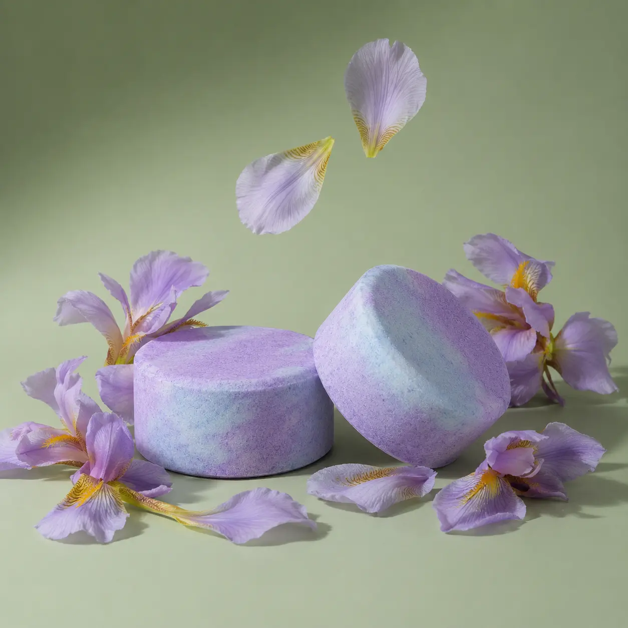 Holy Fizz Lavender Lullaby Shower Steamer purple and mint two pieces surrounded by falling iris flower petals green background aromatherapy