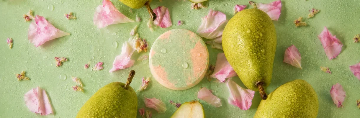 Holy Fizz Fleur de Pear green and peach shower steamer surrounded by fresh green pears and pink flower petals on mint green background